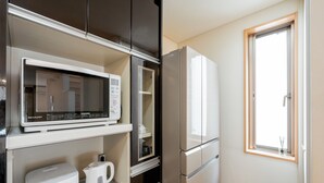 A compact kitchenette with a microwave, kettle, and refrigerator. - Higashi Shinjuku Modern house (Tokyo)
