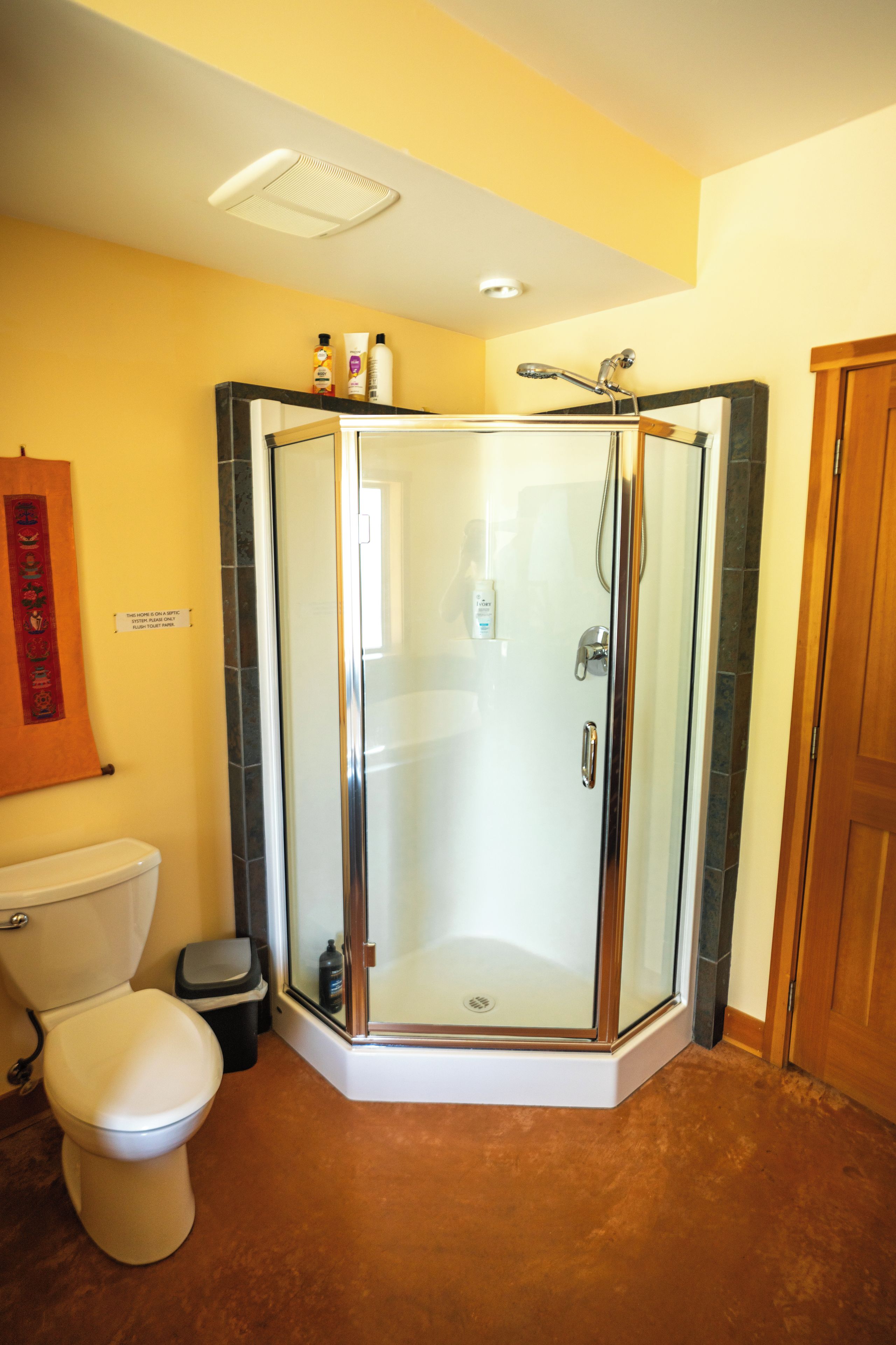 A modern bathroom with a glass-enclosed shower, a toilet, and a sink.