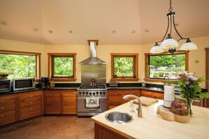 Une cuisine avec des meubles en bois, une cuisinière en acier inoxydable et une grande fenêtre.