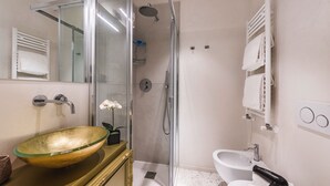 Une salle de bain moderne avec une douche à parois de verre, un grand lavabo ovale et des toilettes.