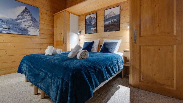 Une pièce en bois avec un lit, des serviettes et des tableaux encadrés accrochés au mur.