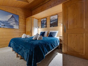 A wooden room with a bed, towels, and framed pictures on the wall.