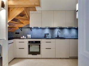 A modern kitchen with a built-in oven, a sink, and a wooden ceiling.