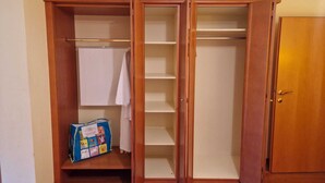 A walk-in closet with open doors, wooden shelves, and a hanging rod.