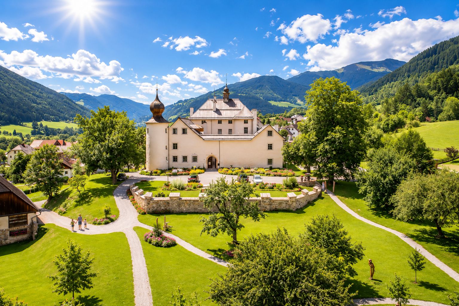 A large, multi-story building with a prominent tower, surrounded by well-maintained gardens and a mountainous backdrop.