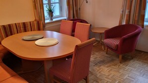 A cozy dining area with a round table, striped chairs, and a red armchair.