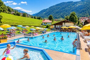 Un área de piscina con varias piscinas, tumbonas y sombrillas.