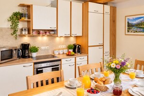 A modern kitchen with built-in appliances, a dining table set for breakfast, and a view of a mountain landscape. - FEWO Haus Gabi | Ski Holiday Murau | Sleeps 8 | Dogs | Kreischberg & Lachtal (Sankt Peter am Kammersberg)