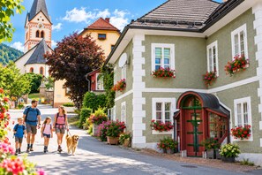A family walking on a cobblestone street with a historic building featuring a red door and flower boxes. - FEWO Haus Gabi | Ski Holiday Murau | Sleeps 8 | Dogs | Kreischberg & Lachtal (Sankt Peter am Kammersberg)