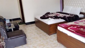 A hotel room with two beds, a sofa, and a small table. - Mezban Hotel & Restaurant (Balakot)