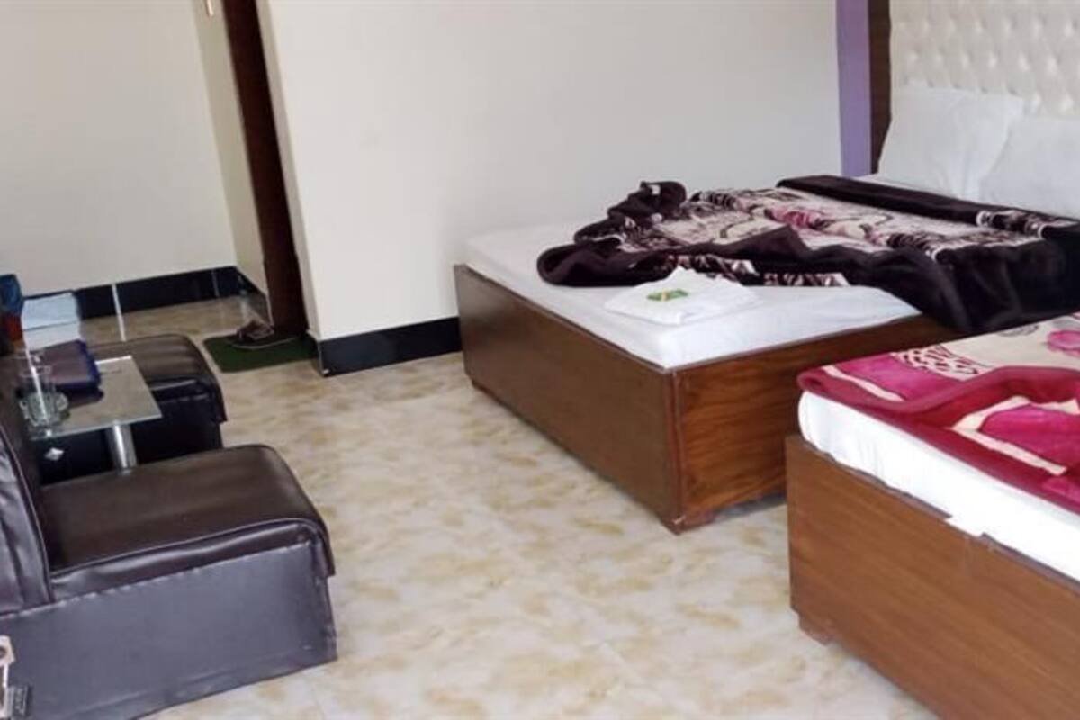 A hotel room with two beds, a sofa, and a small table.