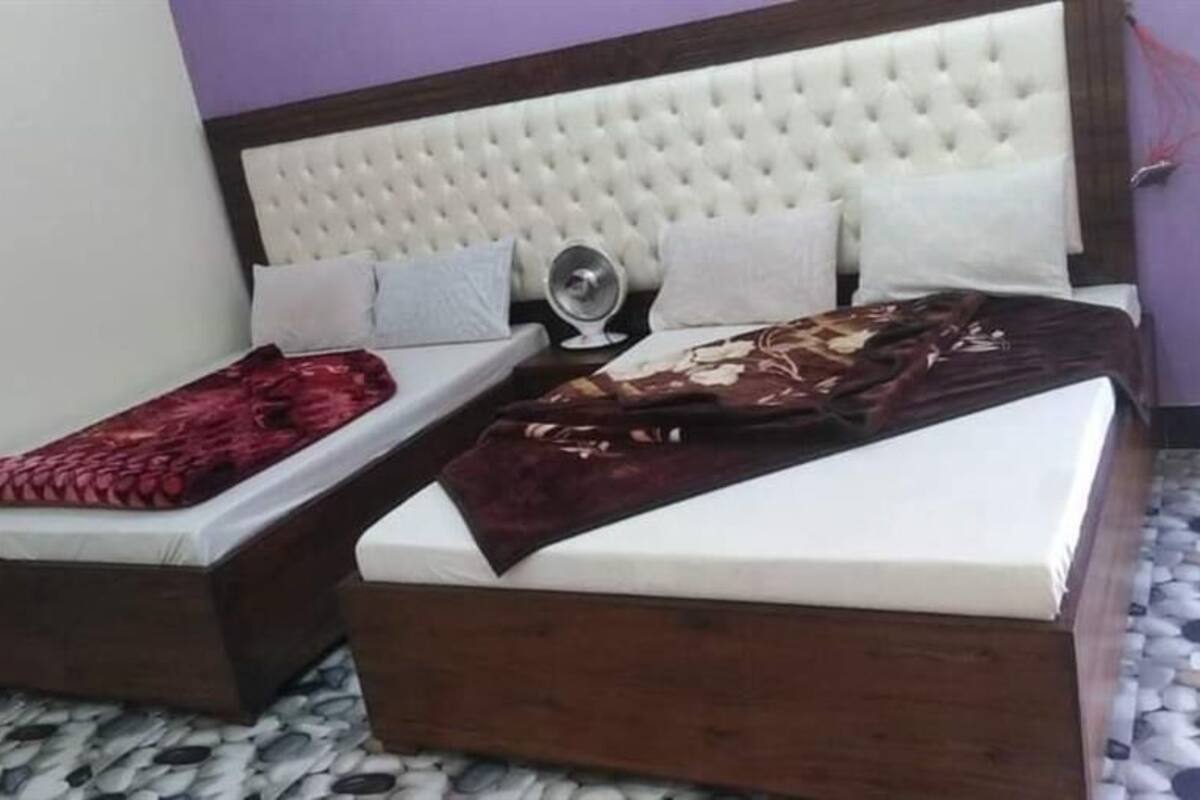 A bedroom with two beds, a white headboard, and a patterned floor.