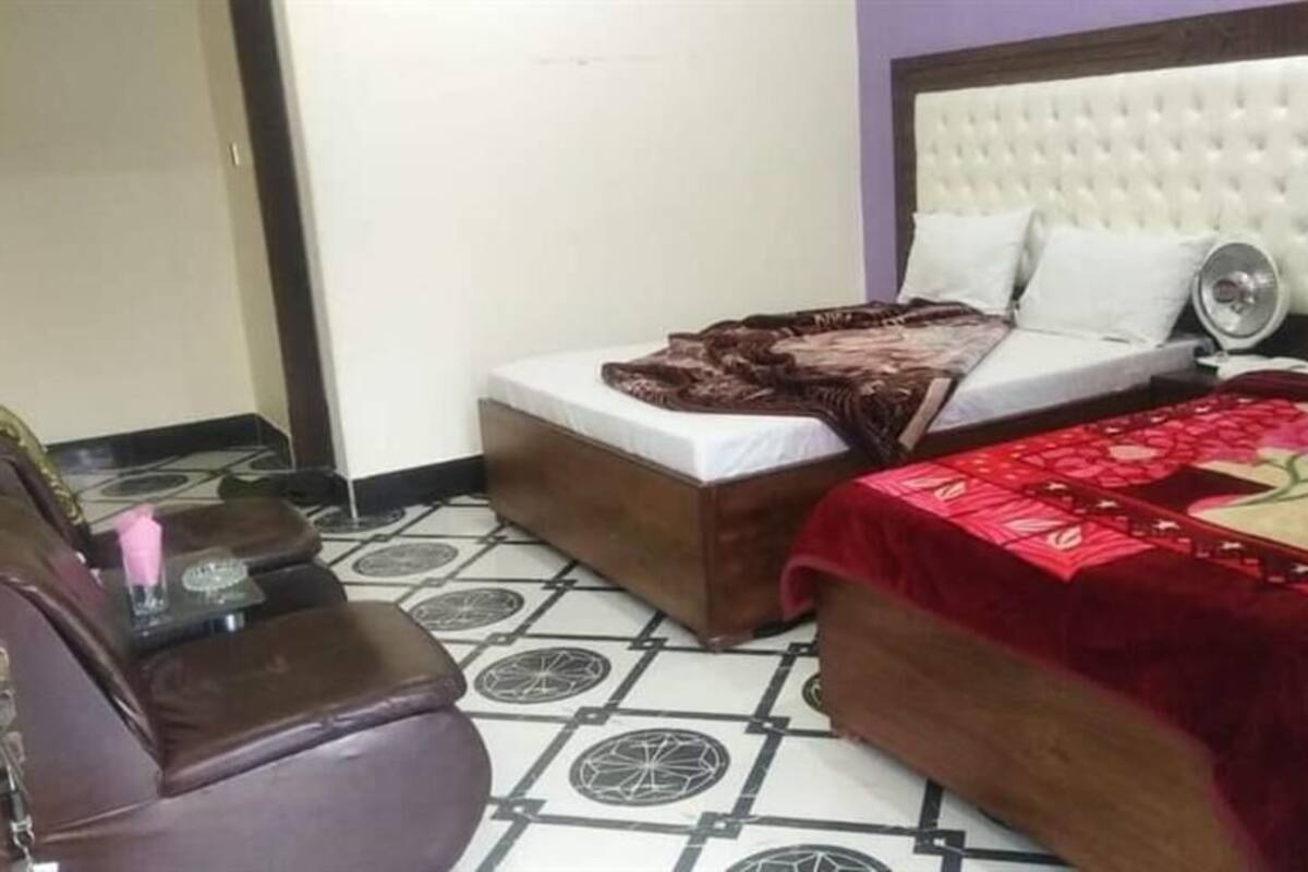 A bedroom with two beds, a sofa, and a small table.