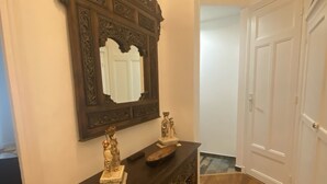 A hallway with a dark wooden console table, a large ornate mirror, and a white door. - 2p Zen Deco apartment ideally located in Paris 17th district (Paris)