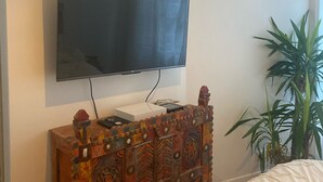 A television mounted on a wall above a wooden cabinet with intricate designs. - 2p Zen Deco apartment ideally located in Paris 17th district (Paris)