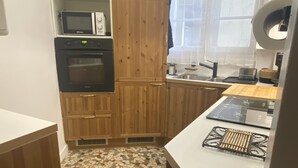 A compact kitchen with wooden cabinets, a microwave, an oven, and a tiled backsplash. - 2p Zen Deco apartment ideally located in Paris 17th district (Paris)