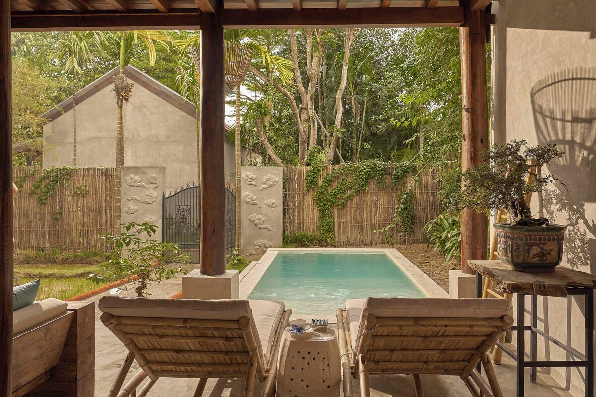 A poolside area with two lounge chairs, a small table, and a potted plant.