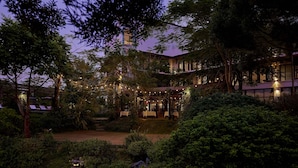 A courtyard with a dining area, surrounded by lush greenery and trees. - aNhill Boutique (Hue)