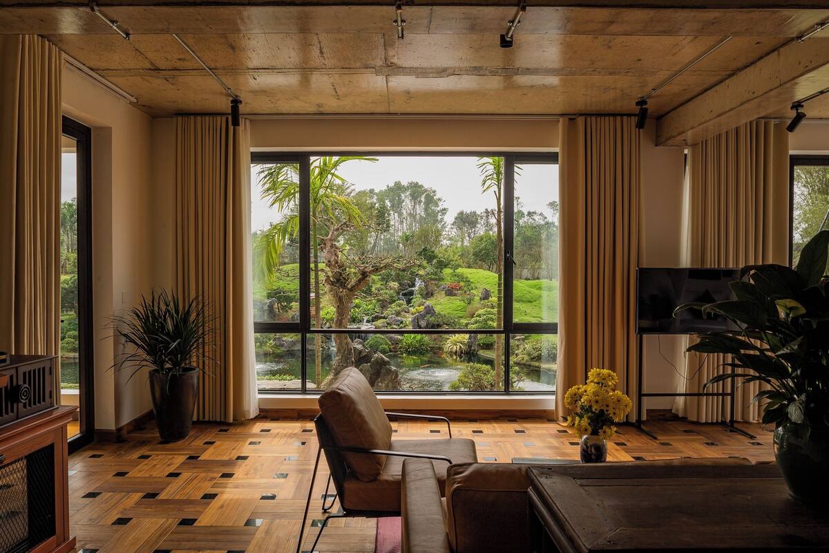 A spacious living room with a large window overlooking a garden, a comfortable seating area, and a flat-screen TV.