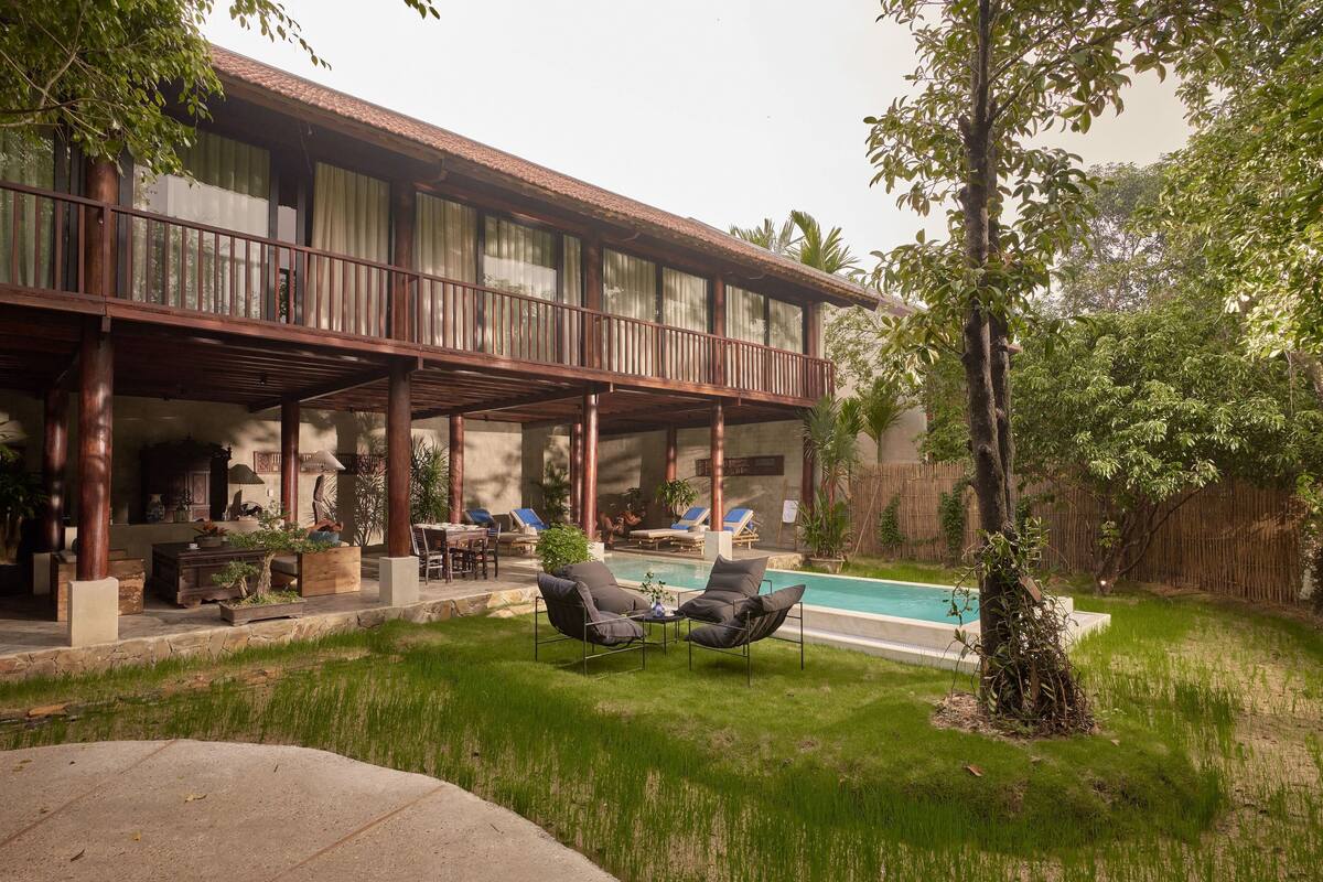 A covered outdoor area with a pool, lounge chairs, and a dining setup.