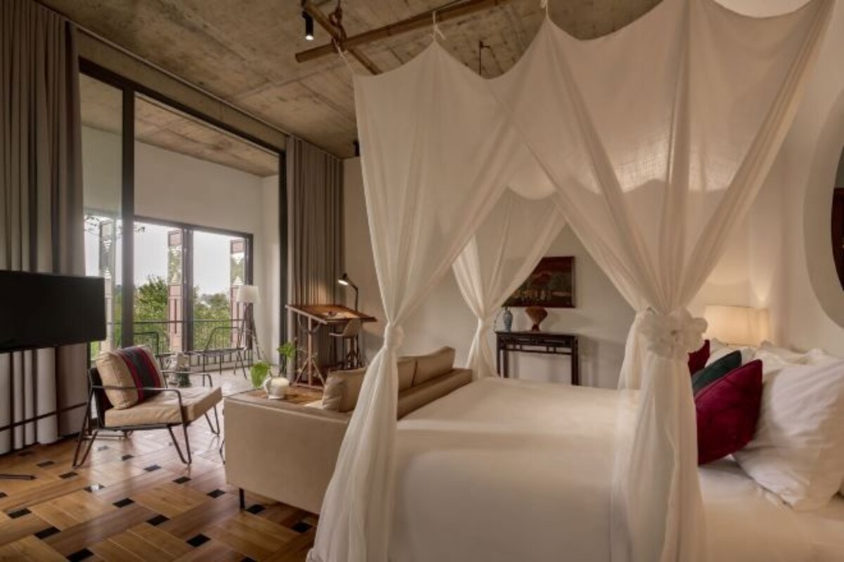 A bedroom with a large bed, a TV, and a view of the outdoors.