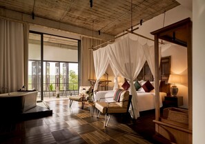A spacious bedroom with a large bed, a sitting area, a bathtub, and a view of the outdoors. - aNhill Boutique (Hue)