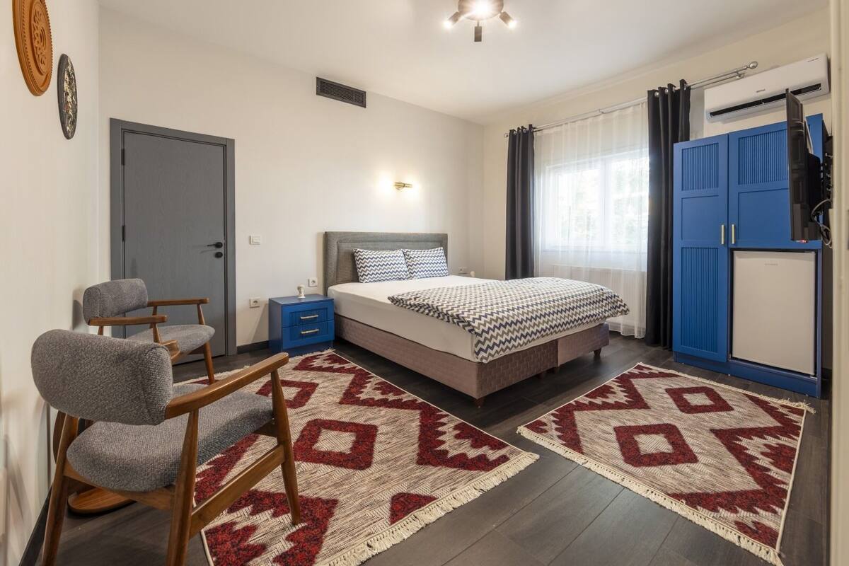 A bedroom with a bed, a chair, a wardrobe, and a small table.