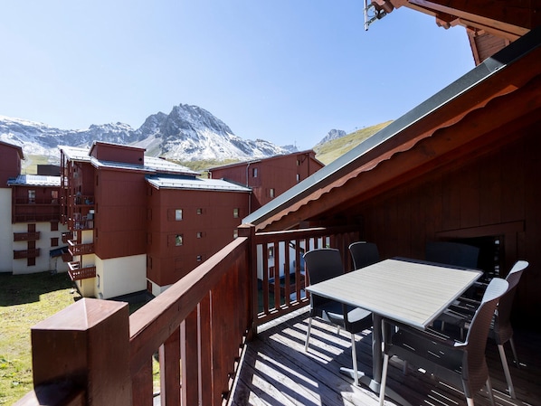 A wooden deck with a table and chairs, overlooking a mountainous landscape.