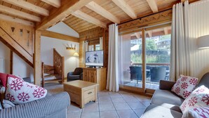 Un salon confortable avec une télévision, des meubles en bois et une porte-fenêtre coulissante donnant sur un espace extérieur.