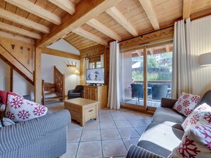 A cozy living room with a television, wooden furniture, and a sliding glass door leading to an outdoor area.