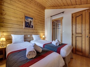 Una habitación con paneles de madera, dos camas, un cuadro enmarcado en la pared y una puerta de madera.