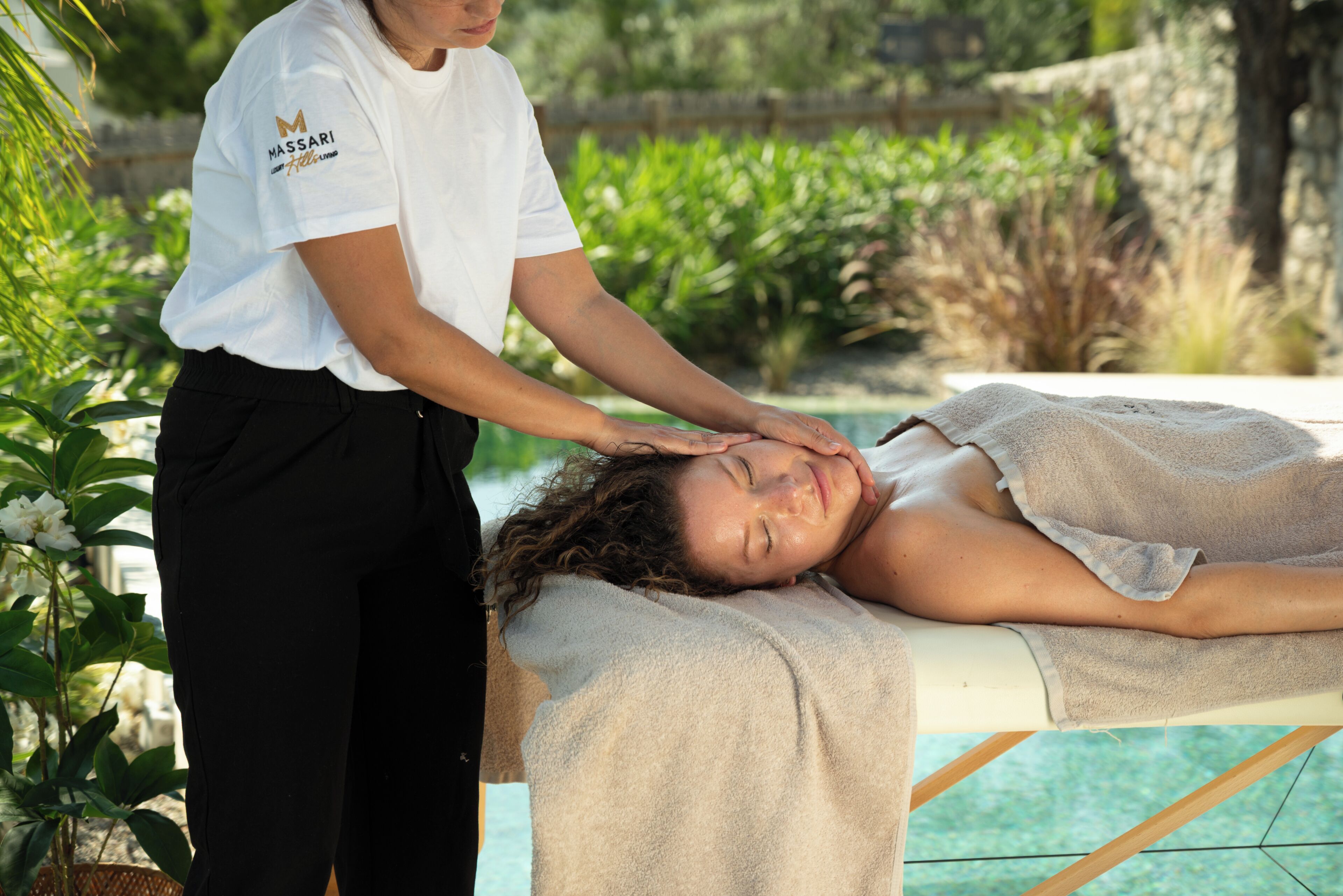 Iemand ontvangt een massage van een massagetherapeut in een spa, met een zwembad op de achtergrond.
