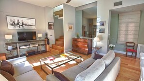 A modern living room with a sofa, coffee table, TV, and a staircase leading to another room. - PRADA PENTHOUSE (terrace, free WIFI, A/C, central, spacious, bright, elegant) (Sevilla)