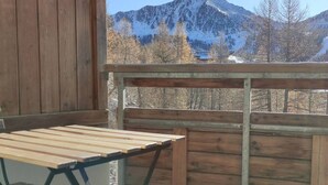 A wooden deck with a table and benches, overlooking a mountainous landscape.