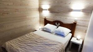 A single bed with a wooden headboard, two bedside lamps, and a white bedside table.