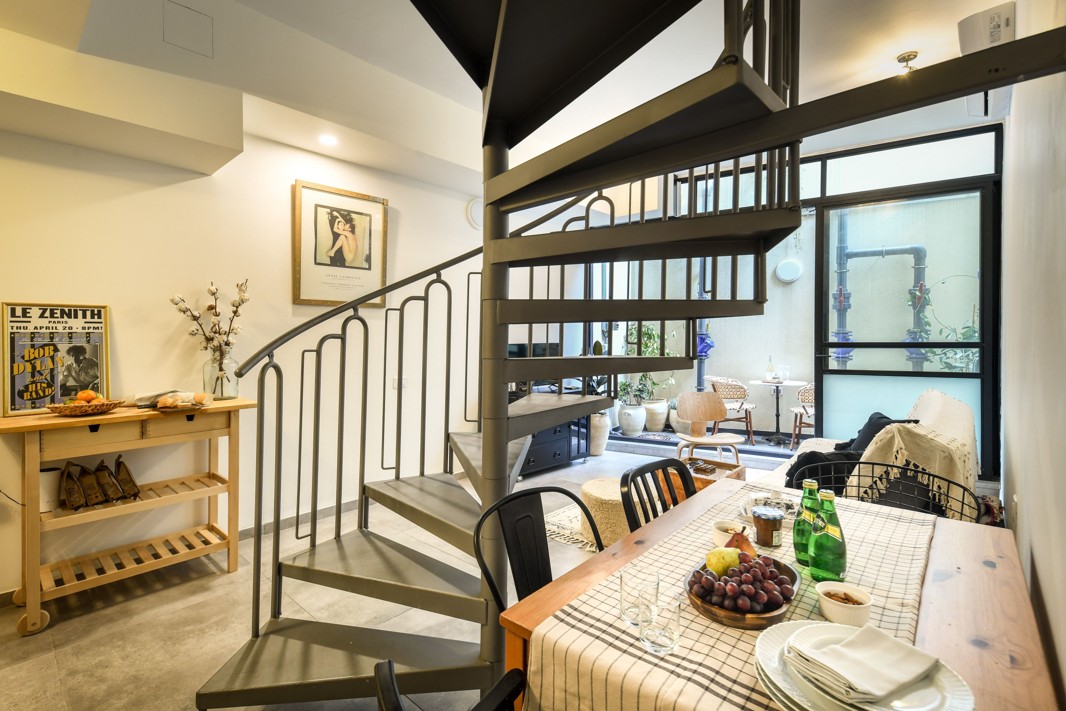 Uma sala de jantar com uma mesa posta para dois, uma escada e uma janela com vista para o exterior.