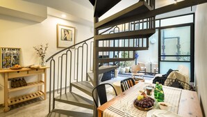 Un coin repas avec une table dressée pour deux personnes, un escalier et une fenêtre donnant sur l’extérieur.