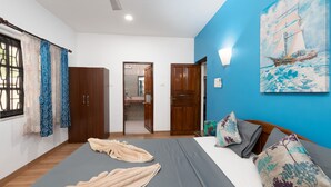 Une chambre à coucher avec un lit, deux armoires en bois, une salle de bain visible à travers une porte ouverte, et un tableau représentant un voilier accroché au mur.