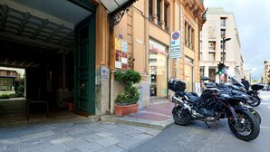 A building with a green entrance, a sign for a shoe store, and motorcycles parked on the street.