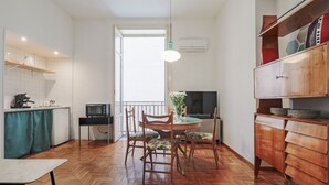 A kitchen with a dining table, chairs, a TV, and a wooden cabinet.