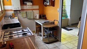 A kitchen with a gas stove, a water heater, and a window with a view of greenery.