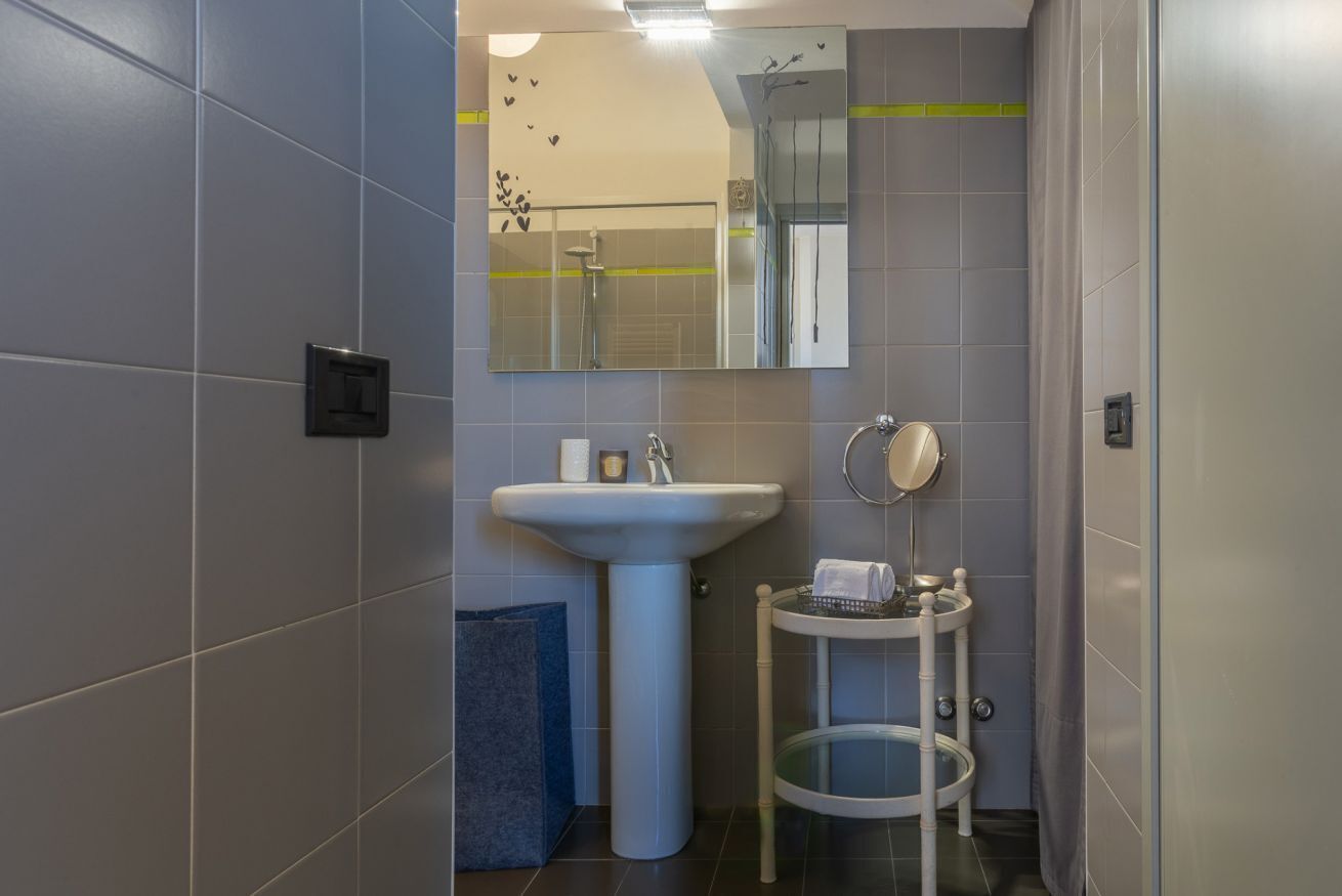 A bathroom with a sink, mirror, towel rack, and a small round table with a towel.