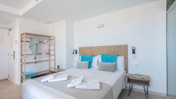 Una habitación de hotel moderna con una cama grande, una cama nido de madera, una mesita de noche y una lámpara de noche pequeña.