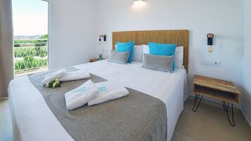 Cama bien hecha con toallas y vistas al verdor exterior.