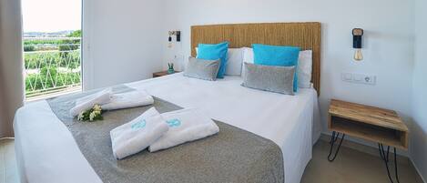 Cama bien hecha con toallas y vistas al verdor exterior.