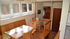A dining area with a wooden table and chairs, a bench, and a window with a view of a brick building. - Idyllically situated vacation apartment 10 min. to the natural beach (Barkelsby)