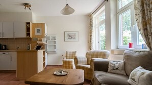 A compact living space with a kitchenette, a wooden coffee table, a sofa, and a chair. - Idyllically situated vacation apartment 10 min. to the natural beach (Barkelsby)