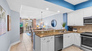 A modern kitchen with white cabinets, a granite countertop, and stainless steel appliances. - Azure 422 ~ Ocean Views ~ 2 Sets of Free Beach Service (Fort Walton Beach)