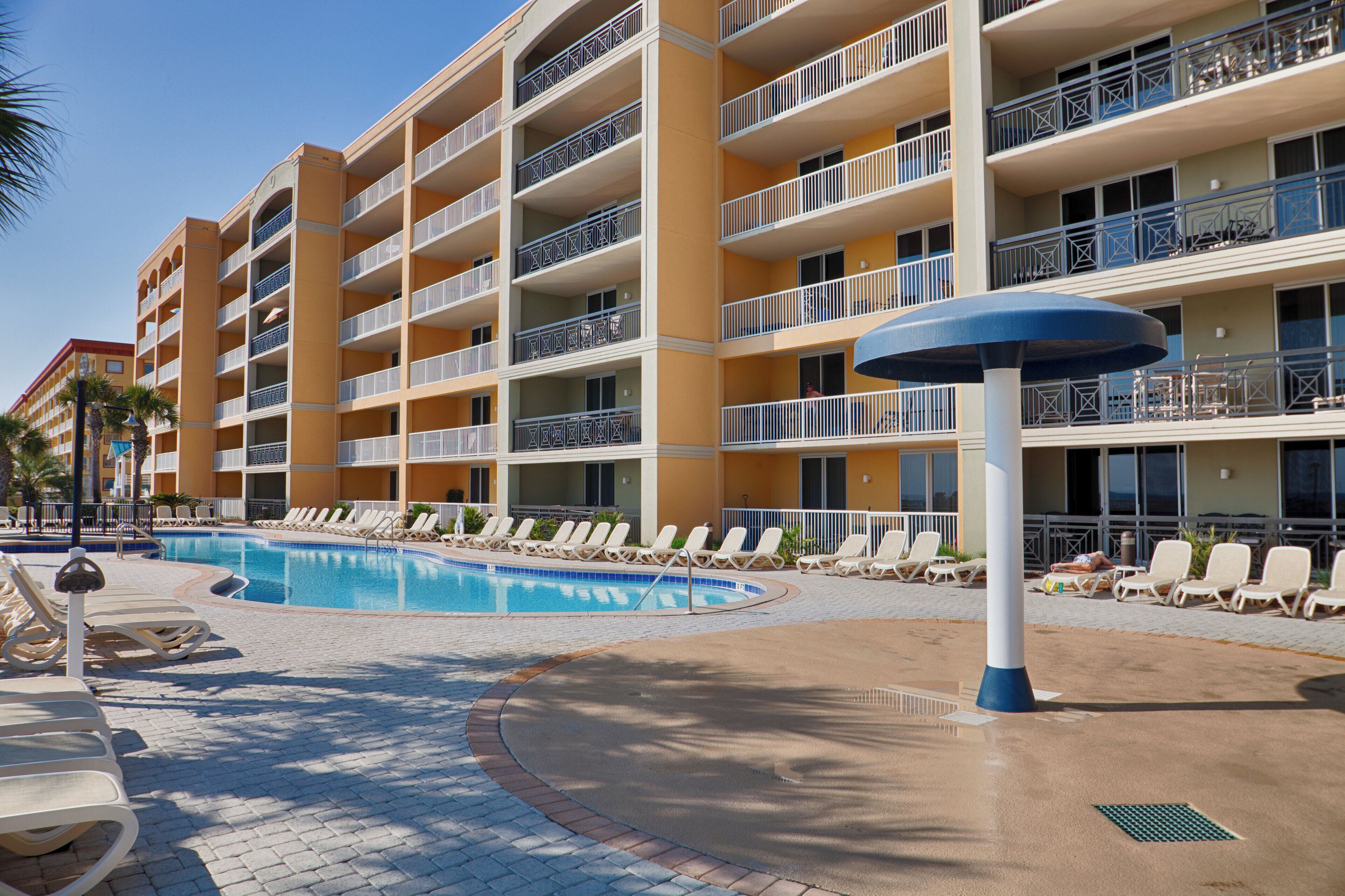 Ein Hotel mit Schwimmbad, mehreren Balkonen und Liegestühlen.