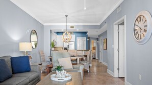 A spacious living room with a sofa, coffee table, and a dining area in the background. - Azure 422 ~ Ocean Views ~ 2 Sets of Free Beach Service (Fort Walton Beach)